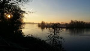 a view of a lake with the sun setting at Ferienwohnung Fischerhütte Xanten in Xanten +4 photos