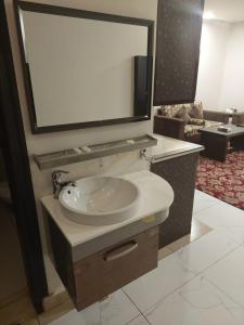 a bathroom with a sink and a large mirror at Zievle Executive Apartments in Buraydah +93 photos