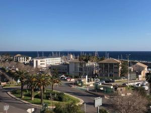 a city street with palm trees and buildings and the ocean at Bastia nid in Bastia