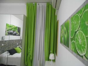 una camera da letto con tende verdi, un letto e uno specchio di Hotel Birillo a La Spezia