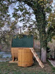a wooden structure with a wooden barrel next to a tree at Bear Secret House in Ćuprija