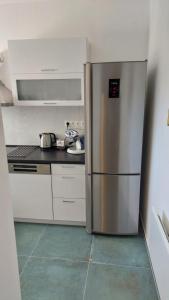 un réfrigérateur en acier inoxydable dans une cuisine blanche dans l'établissement Búzavirág Ház, à Siófok