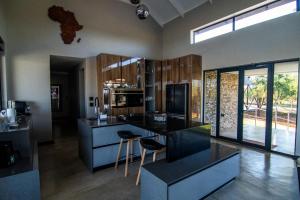 a kitchen with a counter and chairs in a room at Sihlangu Lodge in Marloth Park