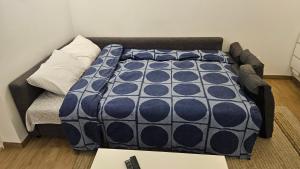 a bed with a blue and white blanket on a couch at CosyNook - refait à neuf proche parc des expositions et aéroport CDG - Parking privé gratuit in Villepinte