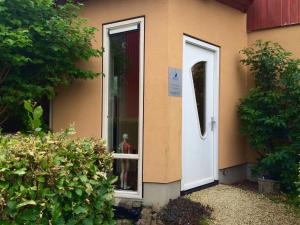 una puerta de una casa con un perro sentado en la ventana en B&B 't Buitenkansje, en Almere