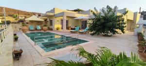 a villa with a swimming pool in front of a house at Villa Urania Kamilari in Kamilari