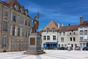 a statue in the middle of a city with buildings at Le manoir étoilé in Neufchâteau