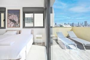 a bedroom with a bed and two chairs on a balcony at Ben Yehuda Dream Penthouse in Tel Aviv