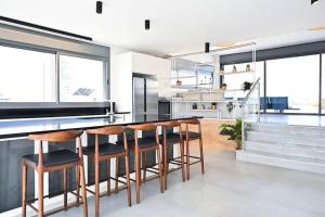 a kitchen with a bar with wooden stools at Ben Yehuda Dream Penthouse in Tel Aviv