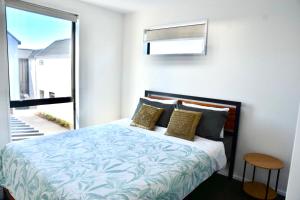 クライストチャーチにあるBrand New Close to CBD 3 Bed 3 Bath with Garageのベッドルーム1室(ベッド1台、大きな窓付)