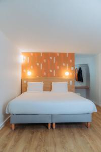 a bedroom with a large bed with a wooden headboard at Kyriad Cannes - Mandelieu in Cannes