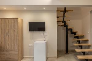 a living room with a tv and a spiral staircase at Uncle tam in Litochoro