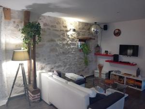 a living room with a white couch and a stone wall at Le Bel Air en Berry in Reigny
