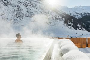 un hombre en un jacuzzi en una montaña nevada en Hotel Klausnerhof, en Tux