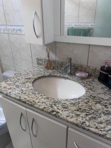 a bathroom counter with a sink and a mirror at Recanto dos pássaros in Penha