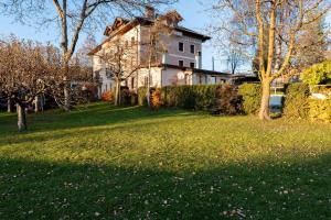 an old house on a green yard with trees at 5 minuti da Asiago - Garage e BBQ in Roana