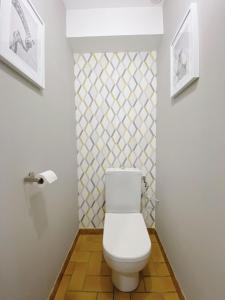 a bathroom with a white toilet and a tile wall at Maison aux portes du centre historique de Dijon avec 3 chambres et garage in Dijon