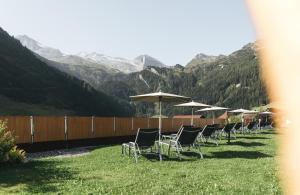 a row of lawn chairs with umbrellas in the grass at Hotel Klausnerhof - Hintertux in Tux