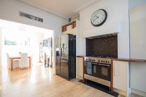 a kitchen with a refrigerator and a clock on the wall at Charming Victorian House w Parking River Walks - Pass the Keys in Windsor