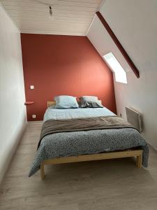 a bedroom with a bed with a red wall at Petite maison sur ferme 5min de la plage idéal professionnel in Trémel