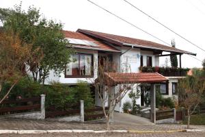 une maison blanche avec un toit rouge dans l'établissement Hospedaria Gãstehaus Enzian, à Treze Tílias