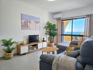 a living room with a couch and a tv at GOLDEN SUN - Sunny Balcony, Sea View, Beach, AC in Carvoeiro