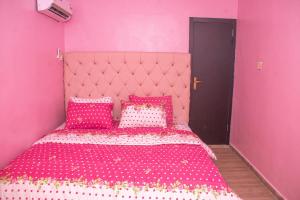 a pink bedroom with a pink bed with pink pillows at Memento Courts in Lagos