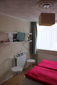 a bedroom with a bed and two chairs and a tv at Kerstins Bed and Breakfast in Egmond aan Zee +6 photos