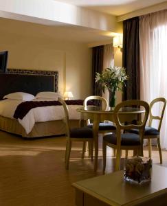 a hotel room with a bed and a table and chairs at Valis Resort Hotel in Volos