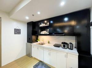 une cuisine avec des placards blancs et un mur noir dans l'établissement The Common Room at Pine Suites Tagaytay, à Tagaytay 15 autres photos