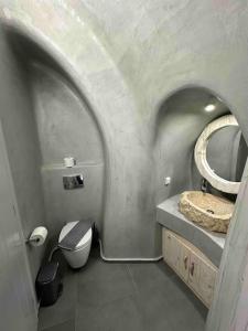 a bathroom with a sink and a toilet and a mirror at Nostos Central Cave House with jacuzzi in Fira