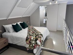Un dormitorio con una cama con almohadas verdes. en Beautifully furnished loft apartment in central Durbanville, en Durbanville