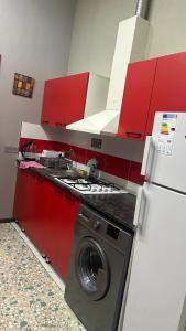 バクーにあるLarge and central apartment in the heart of Baku, close to Icheri Sheher Metro station and the Fountain Squareの赤いキャビネット付きのキッチン(洗濯機付)