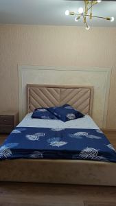 a bed with a blue comforter and blue pillows at Алтын Арман in Kostanay