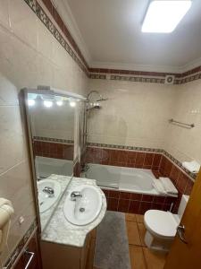 a bathroom with a sink and a toilet and a tub at Superbe appartement vue mer et falaises in Lagos