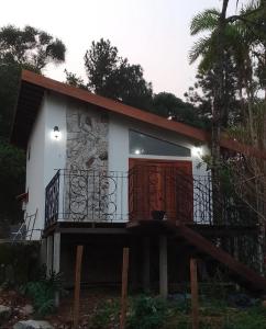 una piccola casa bianca con una grande porta in legno di Chalé do Barão a Santa Maria Madalena