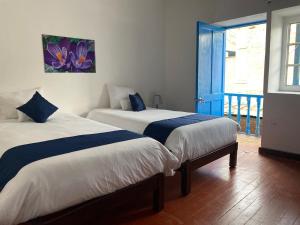 two beds in a room with a door to a balcony at Runa House in Cusco +5 photos