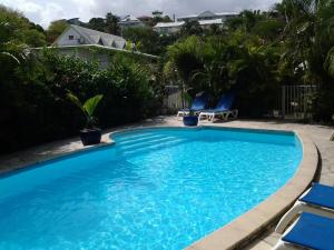a large blue swimming pool with blue chairs in a yard at RESIDENCE BLEU MARINE (Appartement Bleu Océan) in Le Gosier