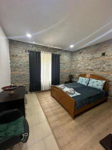 een slaapkamer met een bed en een stenen muur bij Julia's Village Villa in Korçë