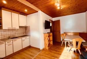a kitchen with white cabinets and a table and chairs at Haus Lena in Solda