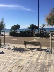 una panchina seduta su un marciapiede vicino alla spiaggia di Studio Océan Bleu a Les Sables-dʼOlonne Altre 5 foto