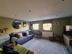 ein Wohnzimmer mit Sofa und Fernseher in der Unterkunft Brisley North Norfolk cosy cottage garden pub and walks in Beetley