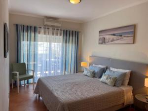 a bedroom with a bed and a large window at Condominio do Mar in Lagos