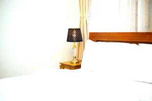 una lámpara sentada en una mesa junto a una cama en Diamond Delight Boutique Hotels, en Moshi
