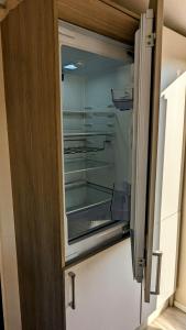 an empty refrigerator with its door open in a kitchen at Jenny and Jamie's holiday home on the edge in Morecambe