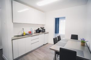a kitchen with white cabinets and a table with chairs at SEB Residence Sibiu II in Sibiu
