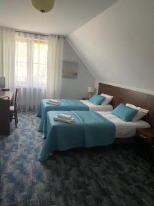 two beds in a hotel room with blue sheets at Hotel Restauracja Cztery Pory Roku in Orneta +31 photos