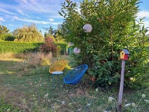 due sedie e una casetta per uccelli accanto ad un albero di Chambre au coeur de la Sologne a Romorantin Altre 2 foto