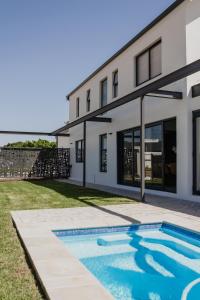 a house with a swimming pool in front of it at Albatross Lodge - Silwerstrand Golf and River Estate in Robertson