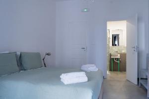 een witte slaapkamer met een bed met handdoeken erop bij LemonHouse in Napels